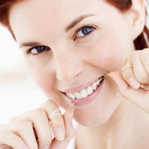 Image of a young female flossing her teeth, Charlotte, NC